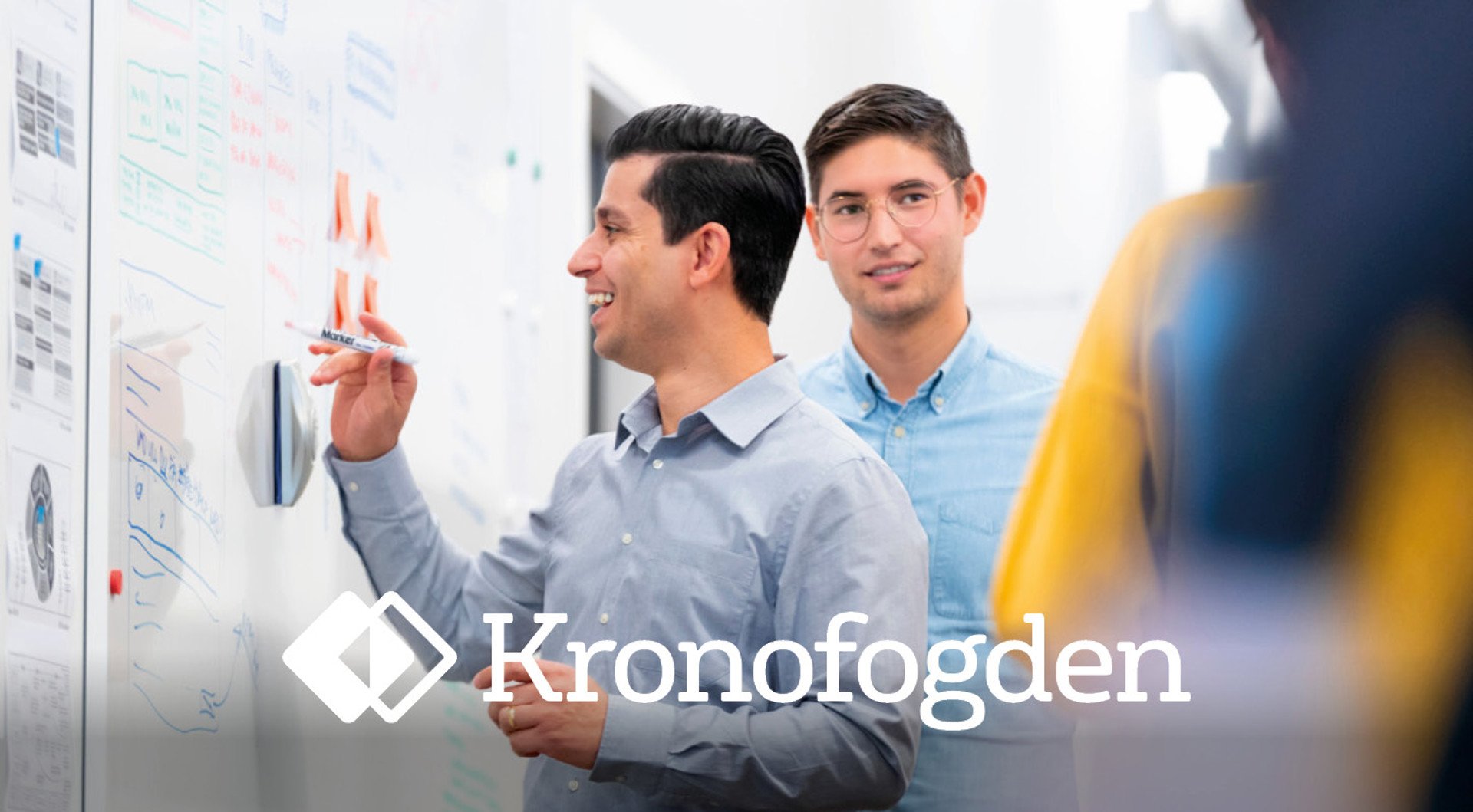 En leende man skriver på whiteboard. Kronofogdens logotyp.