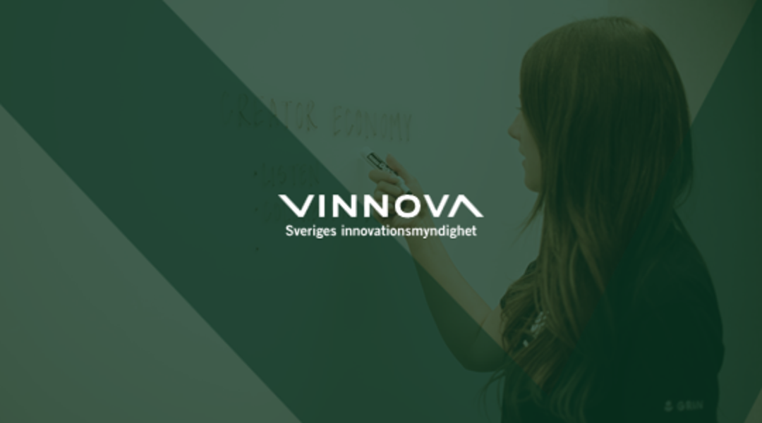 En person med långt hår skriver på en grön tavla. Vinnovas logotyp.