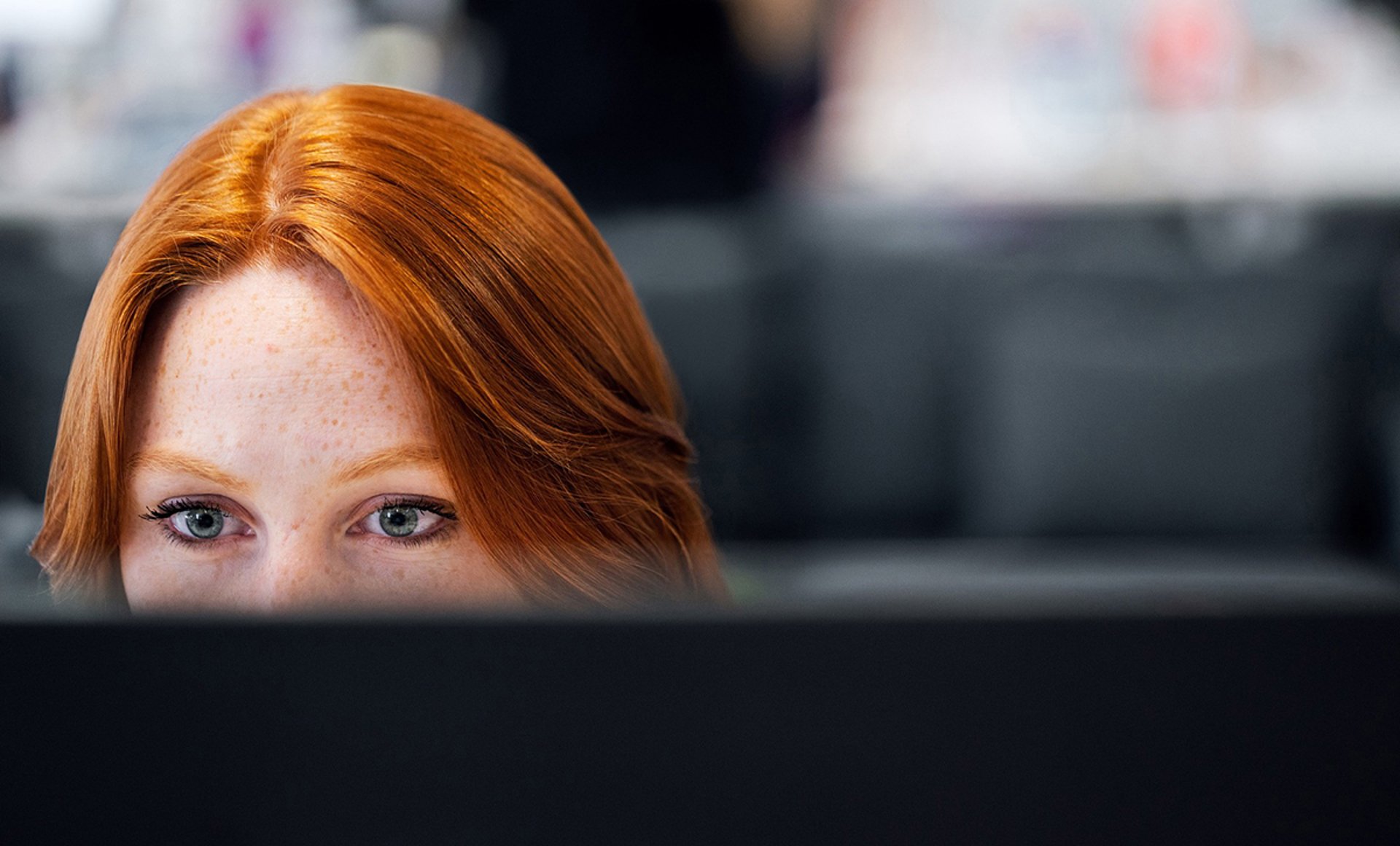 Kvinna syns från ögonen upp bakom datorskärm